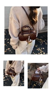 Détail d'un sac Boston marron foncé avec finition brillante et breloque ours
