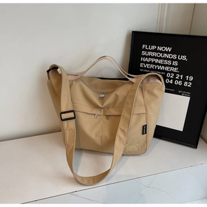 Close-up of khaki tote bag featuring double front zipper pockets and dog embroidery