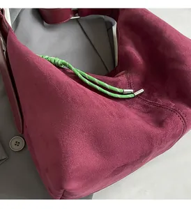 Detail showing the burgundy suede tote bag with a contrasting green woven drawstring accent