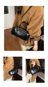 Macro detail of black glossy Boston bag showing embossed text and premium metal zipper