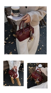 Gros plan sur un sac Boston bordeaux avec logo embossé et finitions dorées chic