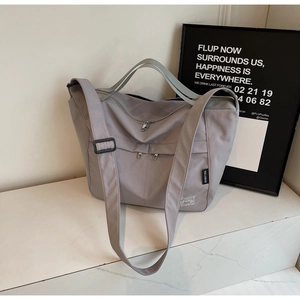 Detail view of large grey nylon tote bag with double front zipper pockets and bear motif