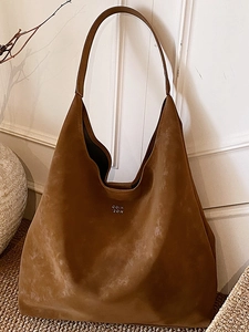 Sac hobo en daim marron avec logo argenté dans un décor minimaliste élégant