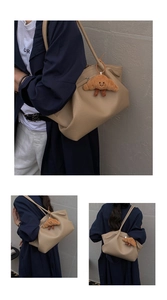 Detail of khaki litchi grain leather tote bag with a cute brown plush pendant