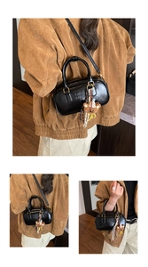 Détail du sac cylindrique noir brillant avec ferrures dorées et breloque ours en peluche