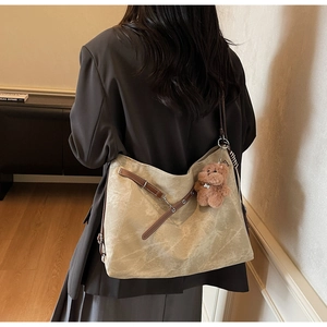 Detailed view of khaki retro tote bag with brown straps and plush bear charm decoration