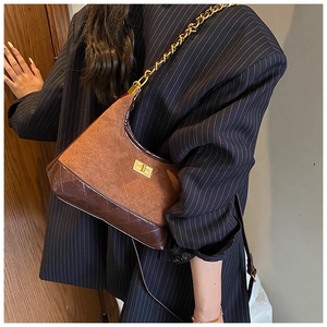 Close-up of brown suede and quilted leather shoulder bag with golden chain strap