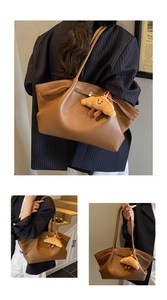 Detailed view of brown litchi pattern leather tote bag with a cute croissant plush pendant