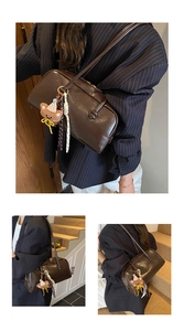 Detail of dark brown vintage oil wax leather bag with white cord and bear charm accessory