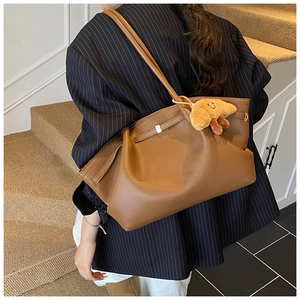 Brown litchi grain leather tote bag featuring a cute croissant plush charm and soft straps