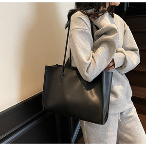 Large capacity black leather tote bag shown on shoulder for daily office commuting