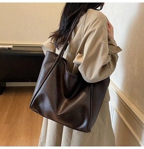 Detail showing deep brown matte leather texture and reinforced piping on tote bag