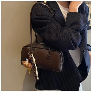 Detail of deep brown glossy bowling bag featuring a cute bear charm and thin shoulder straps