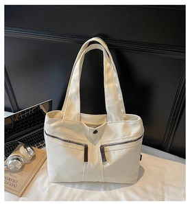 Close-up of cream canvas tote bag with dual zipper pockets and office essentials
