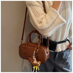 Détail du mini sac Boston marron vintage avec pendentif ours et cuir synthétique poli