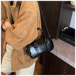 Detail of black leather Boston bag featuring MIRA MIRA embossed logo and gold hardware