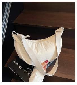 Detail of white nylon crescent bag showing fabric texture on wooden stairs background