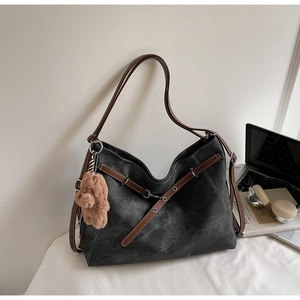 Detail of vintage gray tote bag with leather strap, contrast stitching and bear charm