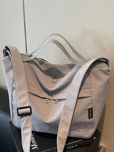 Large waterproof mauve nylon tote bag with multi-zipper pockets and embroidery details