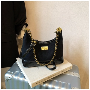 Close-up of quilted black suede bag with gold chain strap and metal swivel lock detail