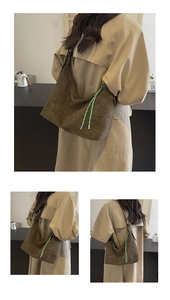 Close-up of brown suede tote bag featuring contrasting green woven rope detail on the side