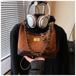 Detail of brown quilted suede crossbody bag featuring gold chain and square twist lock
