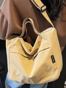 Large beige canvas tote bag with dog embroidery and adjustable strap worn cross-body