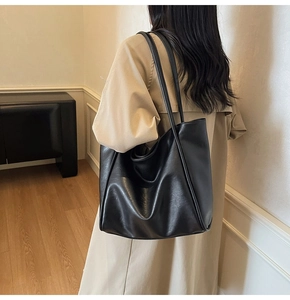 Side view of a large black minimalist tote bag with long straps worn on shoulder