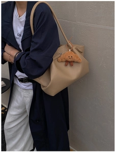 Detail of beige lychee pattern leather tote bag featuring a cute brown plush horn pendant