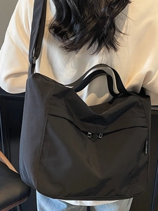 Black large capacity tote bag with relief decor and adjustable strap on a model