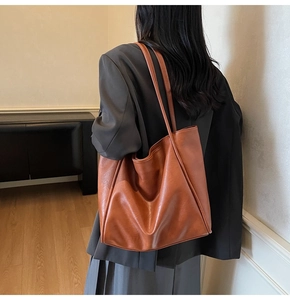 Detail view of brown PU leather tote bag showing fine texture and long double shoulder straps