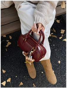 Vue détaillée du sac cylindrique bordeaux avec logo MIRA MIRA et pendentif ours brun