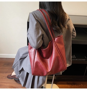 Detail of burgundy leather tote bag with stitching on gray suit commute outfit