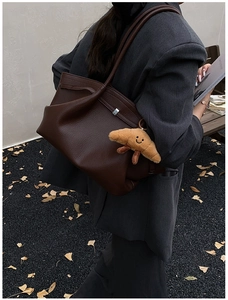 Deep brown lychee texture tote bag with a cute croissant plush charm in a street style view