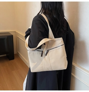 Detail view of beige canvas tote bag with front zip pockets for stylish daily commuting