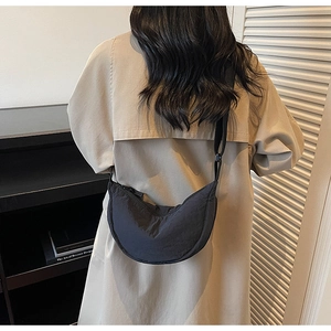 Detailed back view of a black crescent nylon crossbody bag worn with a beige trench coat