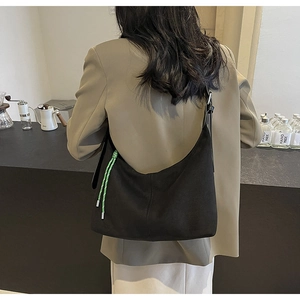 Detailed back view of a black hobo tote bag featuring a vibrant green decorative knot