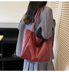 Detail view of the large vintage burgundy tote bag worn by a model in a minimal room