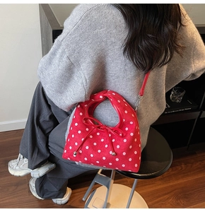 Détail du sac à main rouge à pois avec nœud en cuir et bandoulière amovible pour femme