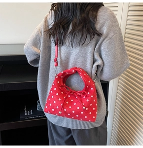Détail du sac rouge à pois avec grand nœud décoratif et bandoulière réglable chic
