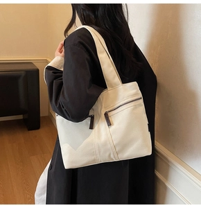 Detail of minimalist canvas tote bag featuring double zipper front pockets and large capacity