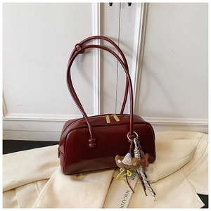 Detail of burgundy patent leather bowling bag featuring a cute bear and star charm
