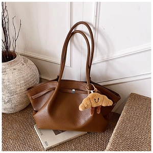 Detailed shot of brown lychee texture tote bag with a cute plush charm on a woven rug