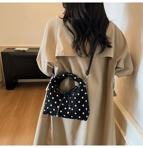 Sac bandoulière noir à pois sur trench-coat beige montrant le style et la coupe