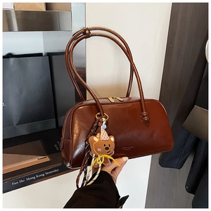 Detail of vintage brown leather bowling bag with a plush bear charm on the strap