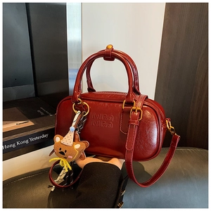 Détail du sac à main en cuir verni bordeaux avec logo Mira Mira et breloque ours