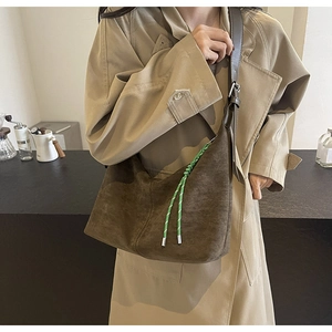 Detail of dark brown suede tote bag with green rope trim on casual trench coat
