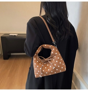 Gros plan du sac en daim marron à pois blancs avec détail de nœud porté par le modèle