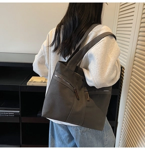 Detail view of a large grey canvas tote bag with functional zipper pockets and leather pulls