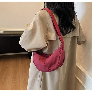 Detail of burgundy crescent dumpling bag showing pleated nylon fabric and wide strap